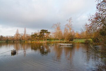 Scenic view of the tranquil lake surrounded by autumn foliage in Bois de Vincennes park during late afternoon light