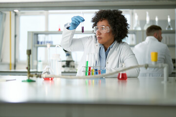 Multiracial female chemist examining chemical substances in a laboratory.
