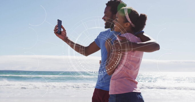 Couple on beach with smartphone, digital interface image over them