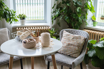 A place for hobbies and knitting. On a white round table there are baskets with yarn for knitting