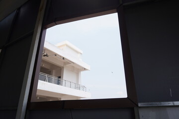 The balcony of a minimalist white multi-storey building seen from the bottom window