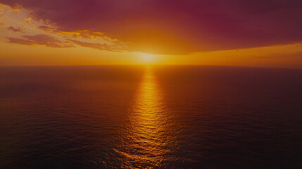 Fototapeta premium Stunning sunset over the ocean. Golden sun dips below the horizon, casting a warm glow on the water. Dramatic clouds add depth to the vibrant sky. Peaceful, serene scene.