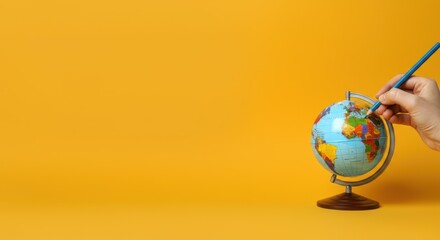 Hand painting miniature globe against yellow background