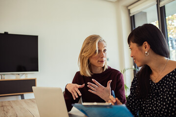 Two professional women collaborating on a project in a modern office