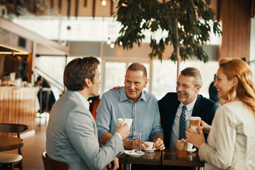 Group of business professionals enjoying coffee and conversation in a modern cafe