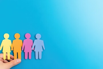Colorful Paper Figures Held in a Hand Against a Blue Background