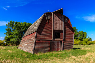Fototapeta premium A red barn with a slanted roof sits in a field