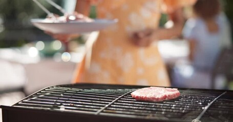 Meat, hand and bbq burger at party for new year celebration, social gathering or lunch. Grill food, friends and people barbecue beef patty, meal and chef cooking with tongs outdoor at cookout closeup