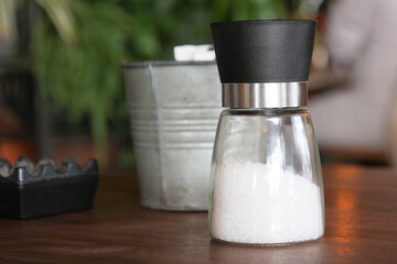 A stylish glass salt shaker beautifully displayed on a rustic wooden table