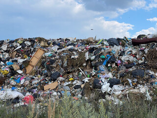A view of a landfill where waste fills the space and hangs over the ground