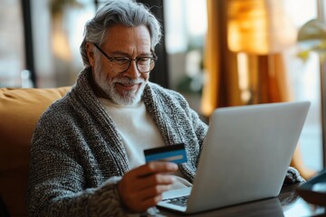 Middle-aged man using laptop for online banking with credit card in cozy home office