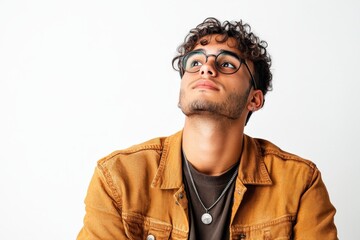 Fototapeta premium Thoughtful Young Man in Casual Outfit Looking Upward Against a Light Background
