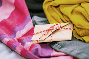 gift envelope made of thick kraft paper, tied with red and white ribbon, rests on fabric, evoking...