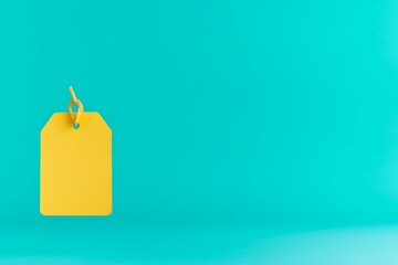 Naklejka premium A bright yellow tag hangs against a vibrant turquoise background, creating a striking visual contrast.
