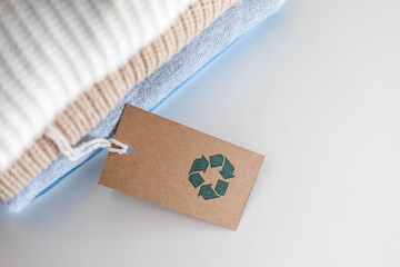 Knitted warm clothes neatly folded heap with craft tag recycling material circle arrow closeup