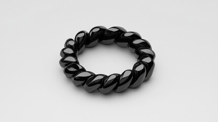 Obraz premium Glossy black twisted metal chain ring on a neutral background showcasing elegance and modern design for jewelry collections.