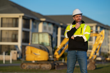 Obraz premium Construction man industry with excavator at industrial site. Worker in helmet build with bulldozer. Engineer work with builder contractor in hardhat. Excavation foreman with tractor.