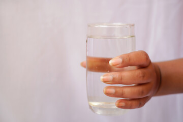 Close up woman hand holding a glass of drinking water on white background, advertising of fresh pure beverage.