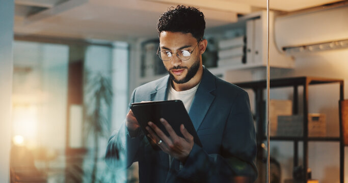 Man, tablet and reading at night in office at startup with scroll, contact or check notification for feedback. Person, touchscreen and click on app with planning, project or review at creative agency