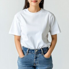 Obraz premium Female Model in Plain White T-Shirt and Denim Jeans Posing Confidently Against Minimalist Background for Stylish Fashion Imagery