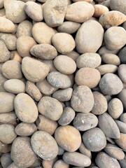 Smooth stone wall background with pebbles on the beach and a textured rocky surface