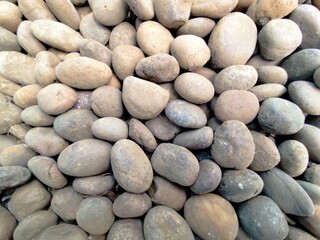 Smooth stone wall background with pebbles on the beach and a textured rocky surface