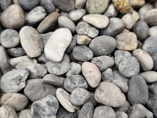 Smooth stone wall background with pebbles on the beach and a textured rocky surface