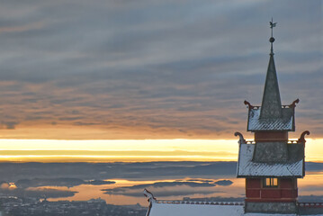 the sunset at Holmenkollen, the sun shines between clouds and the snow-covered landscape in Oslo on...