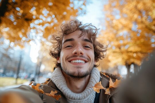 Smiling man in autumn leaves, close-up selfie. Perfect for blogs, social media, or fall themed projects.