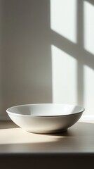 Fototapeta premium White bowl rests on light wood surface in sunlit room