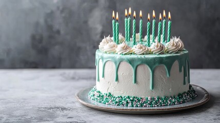 A beautifully decorated birthday cake rests on a silver platter, showcasing ten green candles glowing brightly on top