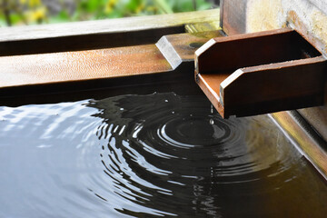 檜の露天風呂の湯口から落ちる一滴のしずくと水紋