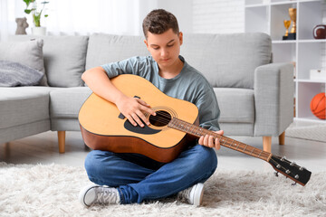 Teenage boy playing guitar at home