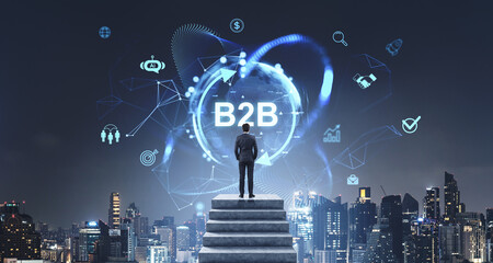 Businessman viewing glowing B2B network icons over cityscape at