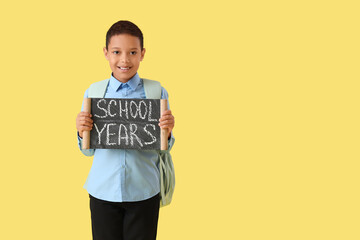 African-American boy holding chalkboard with text SCHOOL YEARS on yellow background