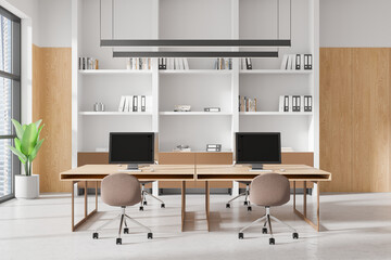 Modern coworking office interior with wooden furniture and computers on desks, bright natural light, and shelves in the background. 3D Rendering