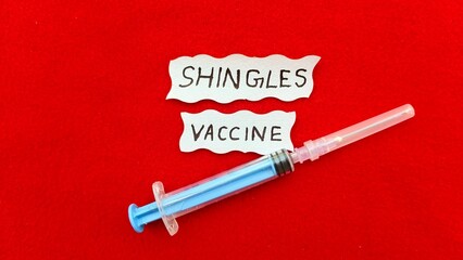 Shingles skin rash disease virus prevention and protection antibodie immunity vaccination or injection concept. Syringe near Shingles vaccine word or text. Closeup top view.