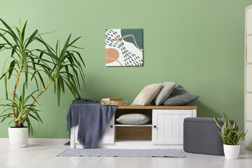 Interior of stylish living room with soft cushions and blanket on cabinet