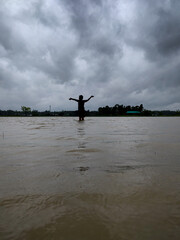 Silhouette of a Person Standing in Flooded Water Against a Dramatic Overcast Sky