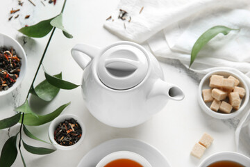 Fototapeta premium Stylish tea pot, cubes of sugar and green twig on marble background, closeup
