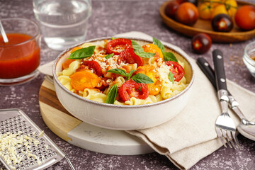 Bowl of tasty pasta with tomato and basil on grunge background