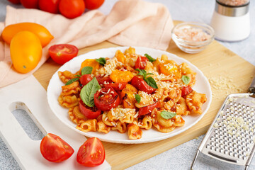 Plate of tasty pasta with tomato and basil on light grunge background