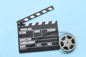 Movie clapper with film reel on blue background