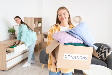 Young woman with clothes for poor people at home