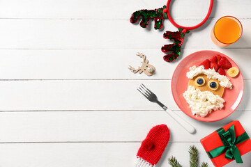 Plate with pancake in shape of Santa Claus on white wooden background