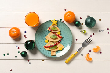 Plate with pancakes in shape of Christmas tree on white wooden background