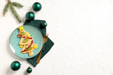 Plate with pancakes in shape of Christmas tree on white grunge background