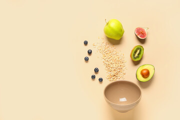 Empty bowl with oatmeal and ingredients on beige background