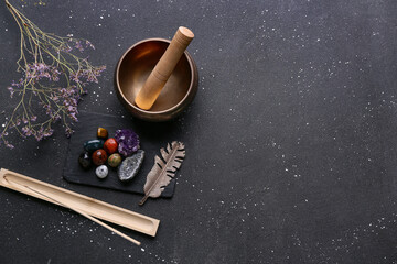 Set of chakra stones, flowers, incense and Tibetan singing bowl on dark background