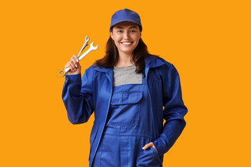 Young female mechanic with wrench on yellow background. Woman in male profession concept